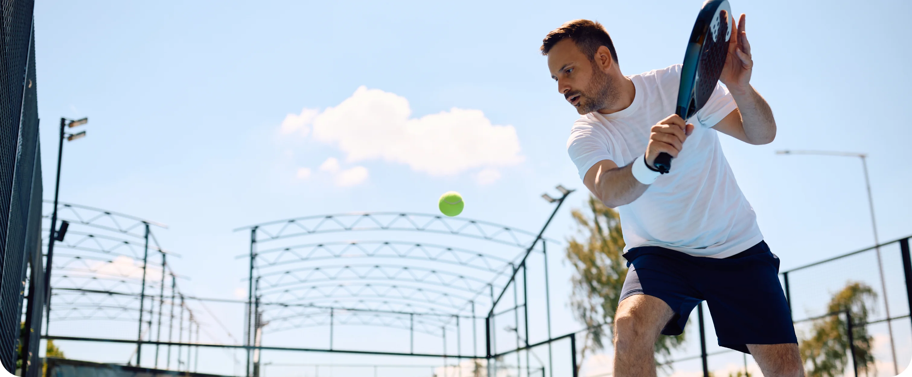 Padel player shaping a backhand on an outdoor court